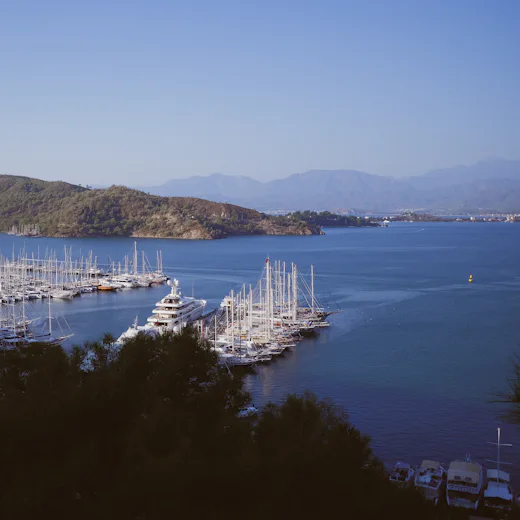 Dağların eteğindeki bir marinada yan yana bağlı çok sayıda yat.